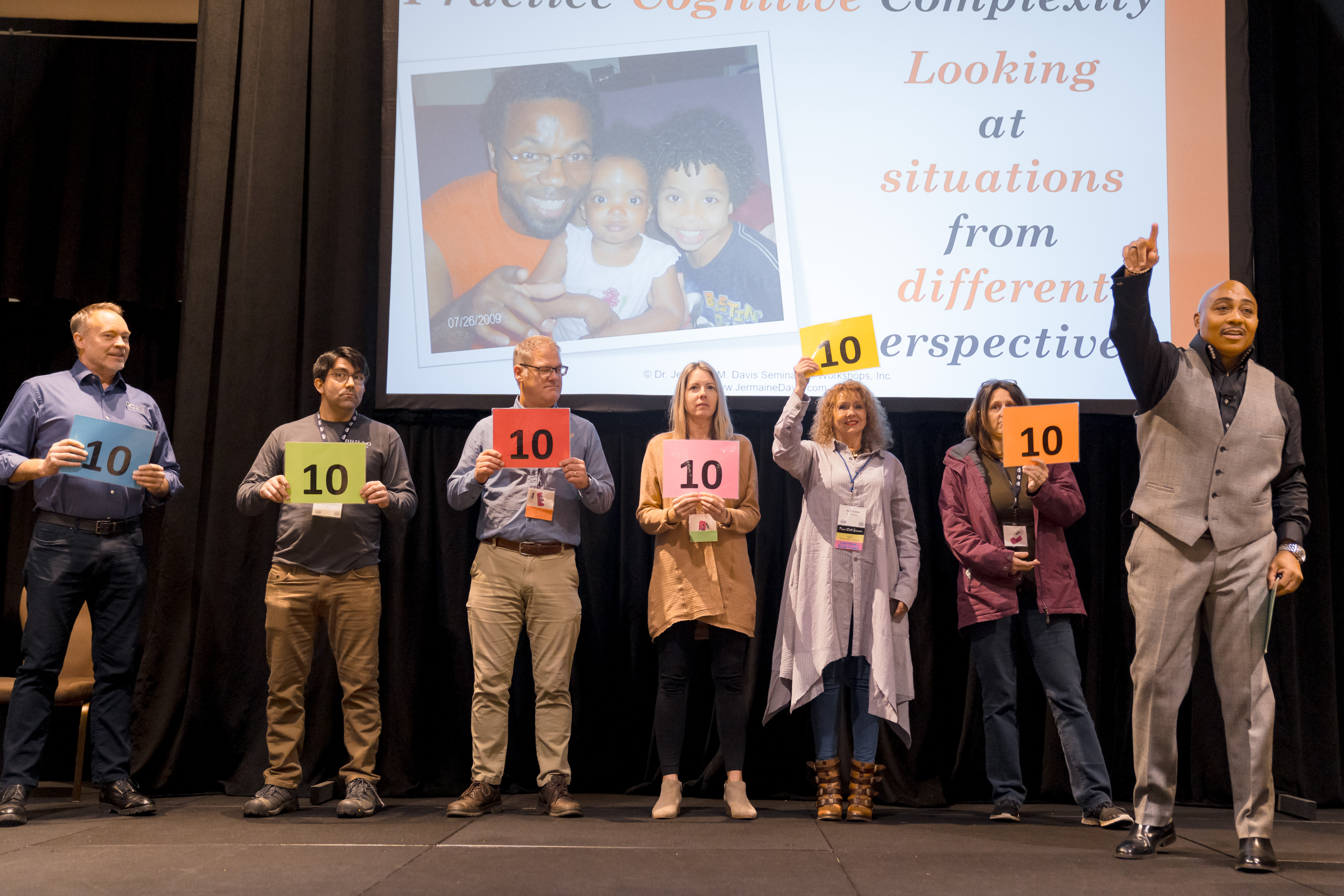 Expo attendees on stage holding up score cards during an interactive game